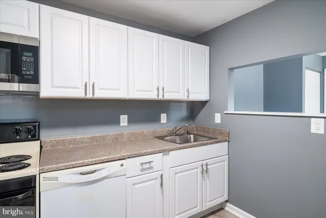 a kitchen with granite countertop white cabinets and sink