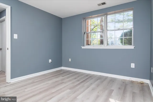 a view of an empty room with wooden floor and windows