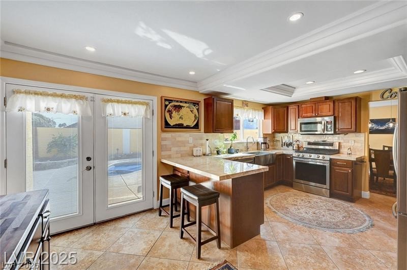 2410 Doherty Way Henderson, NV 89014 - Photo 20 of 63 Kitchen with stainless steel appliances, a peninsula, french doors, decorative backsplash, and light countertops