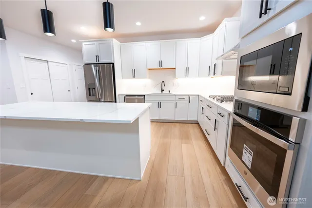 a large kitchen with stainless steel appliances kitchen island granite countertop a stove a sink and a refrigerator