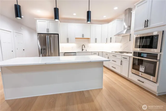 a large kitchen with stainless steel appliances granite countertop a stove a sink and a refrigerator