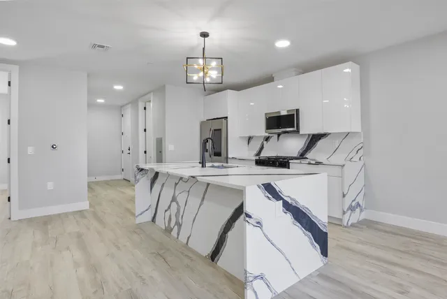 a kitchen with stainless steel appliances granite countertop a sink a stove and a refrigerator