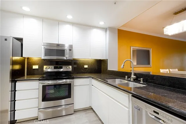 a kitchen with stainless steel appliances a stove a sink and microwave