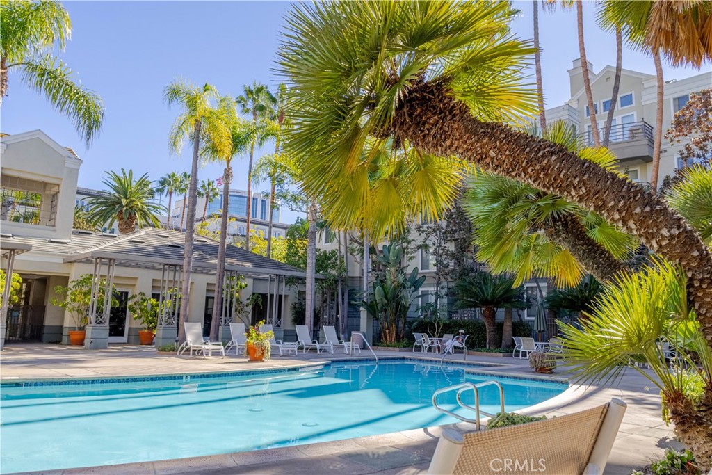 2233 Martin, Unit 108 Irvine, CA 92612 - Photo 22 of 34 a view of a swimming pool with a lawn chairs under palm trees