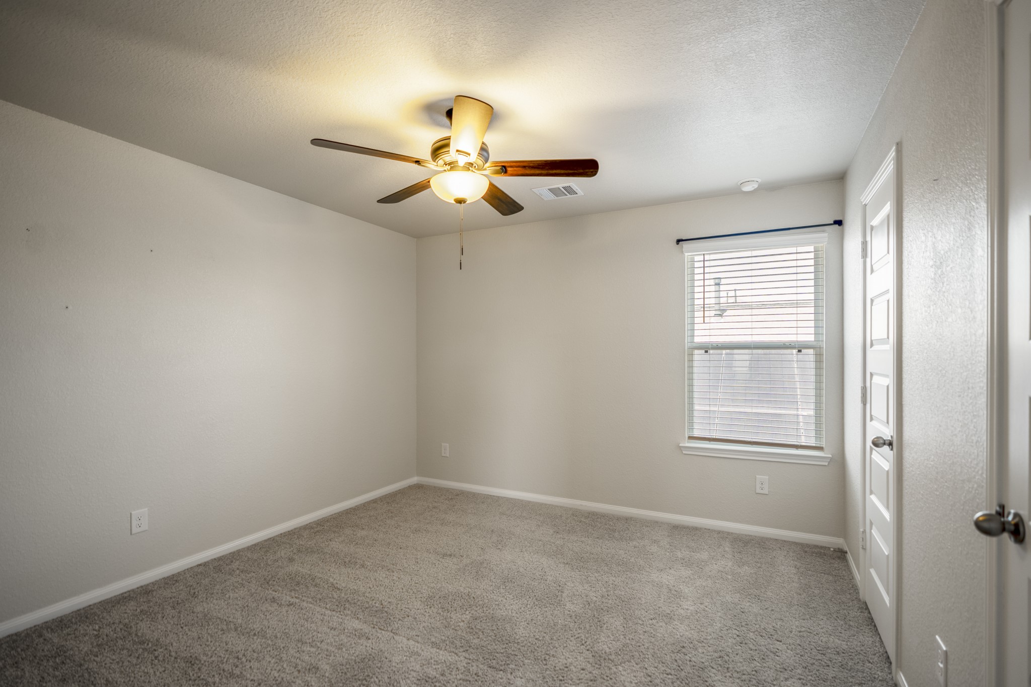 2355 Mount Locke Path Conroe, TX 77301 - Photo 33 of 47 Stepping into the fourth bedroom, this upstairs space offers neutral carpeting, a ceiling fan and natural light from the window. Along the right wall, both doors open into the impressively spacious closet, continuing the standout storage found throughout the home’s bedrooms.