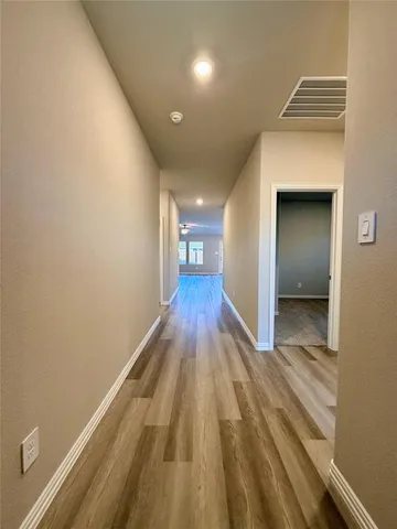 a view of a hallway with wooden floor and a bathroom