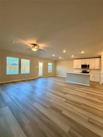 a view of empty room with wooden floor and windows