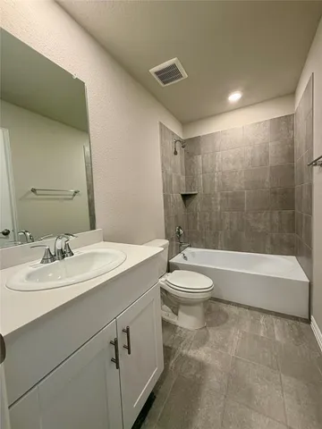 a bathroom with a granite countertop sink toilet a mirror and bathtub