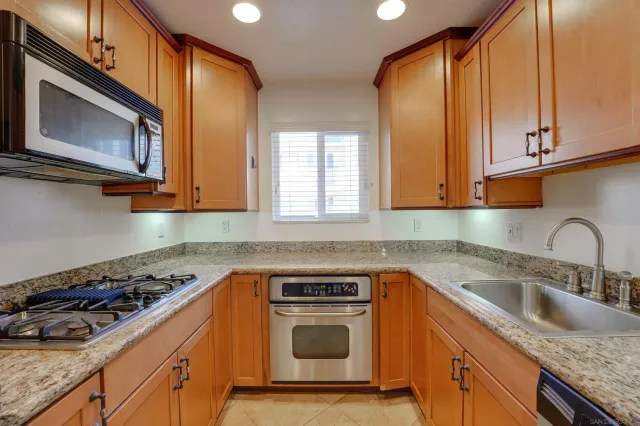 a kitchen with granite countertop a sink a stove microwave and cabinets