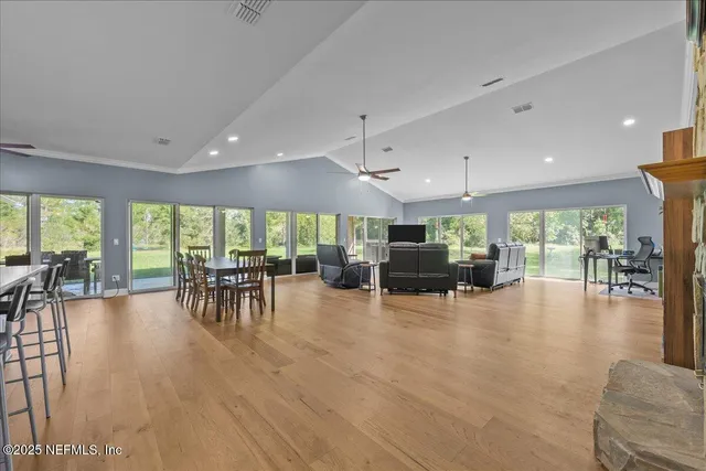 a kitchen with stainless steel appliances granite countertop a refrigerator a sink dishwasher a stove and a dining table with wooden floor