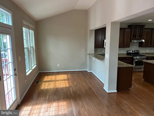 wooden floor in an empty room with a kitchen and a window