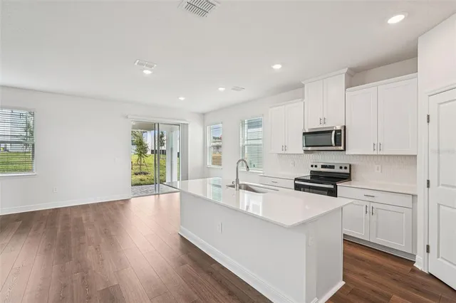 a kitchen with granite countertop a stove top oven a sink a counter space and cabinets