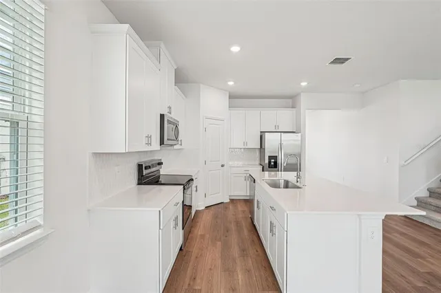 a kitchen with white cabinets sink and stainless steel appliances