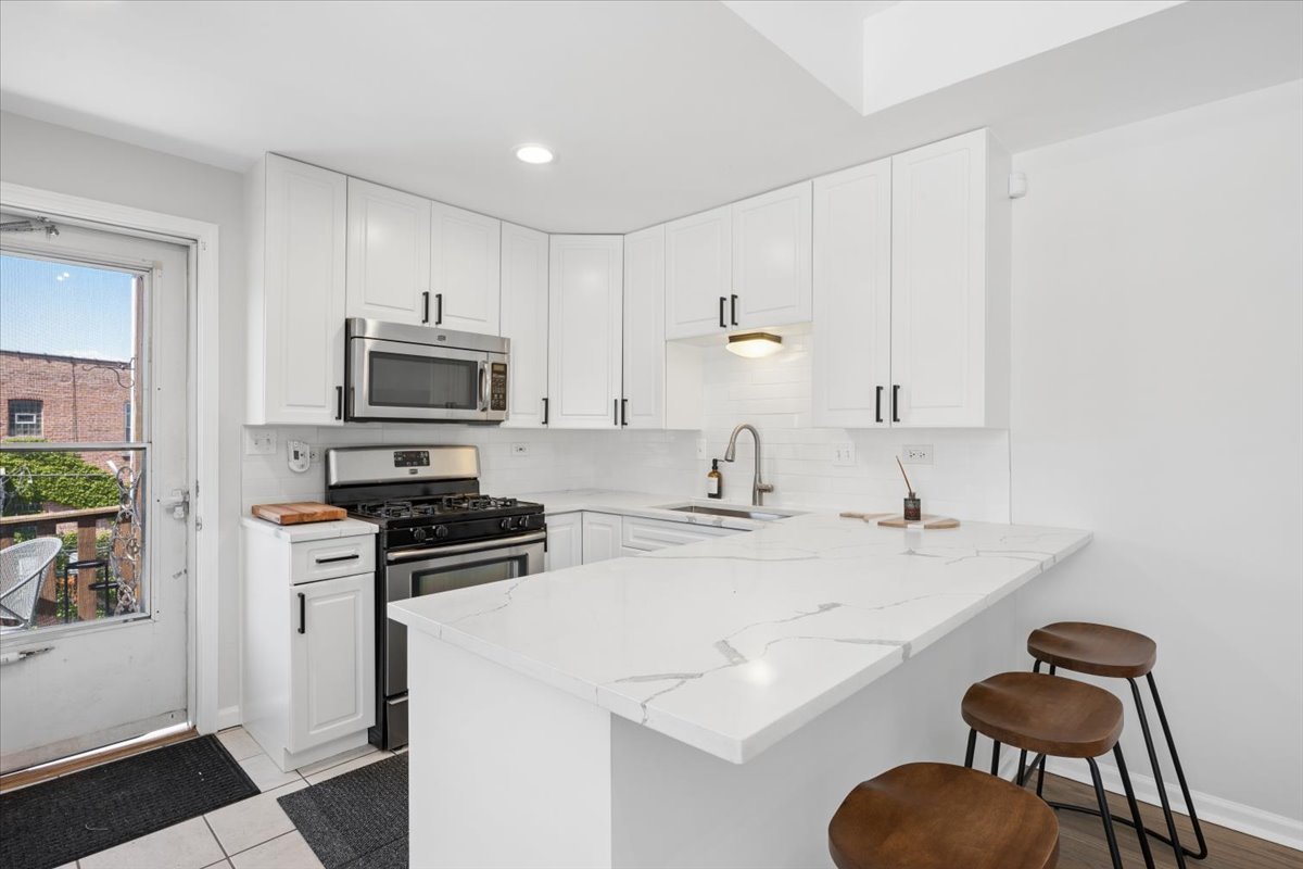 6348 North Magnolia Avenue, Unit 3 Chicago, IL 60660 - Photo 13 of 19 a kitchen with stainless steel appliances a stove a sink a microwave and cabinets