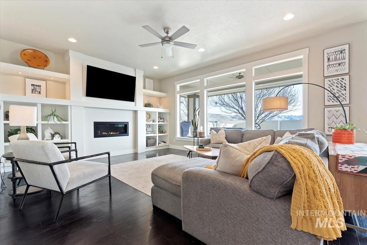 8014 South Bogus Ridge Way Boise, ID 83716 - Photo 41 of 44 Living area with built in features, a ceiling fan, dark wood-style floors, a glass covered fireplace, and recessed lighting