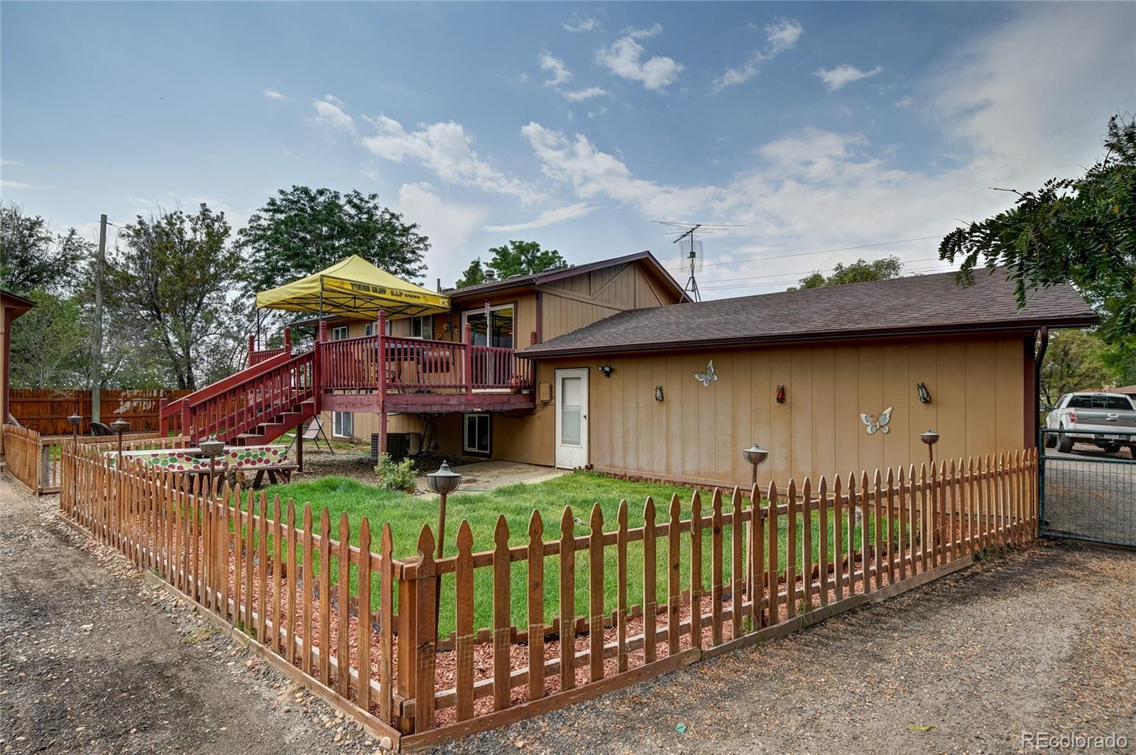 820 South Denver Avenue Fort Lupton, CO 80621 - Photo 19 of 40 a view of a wooden house with large trees and wooden fence