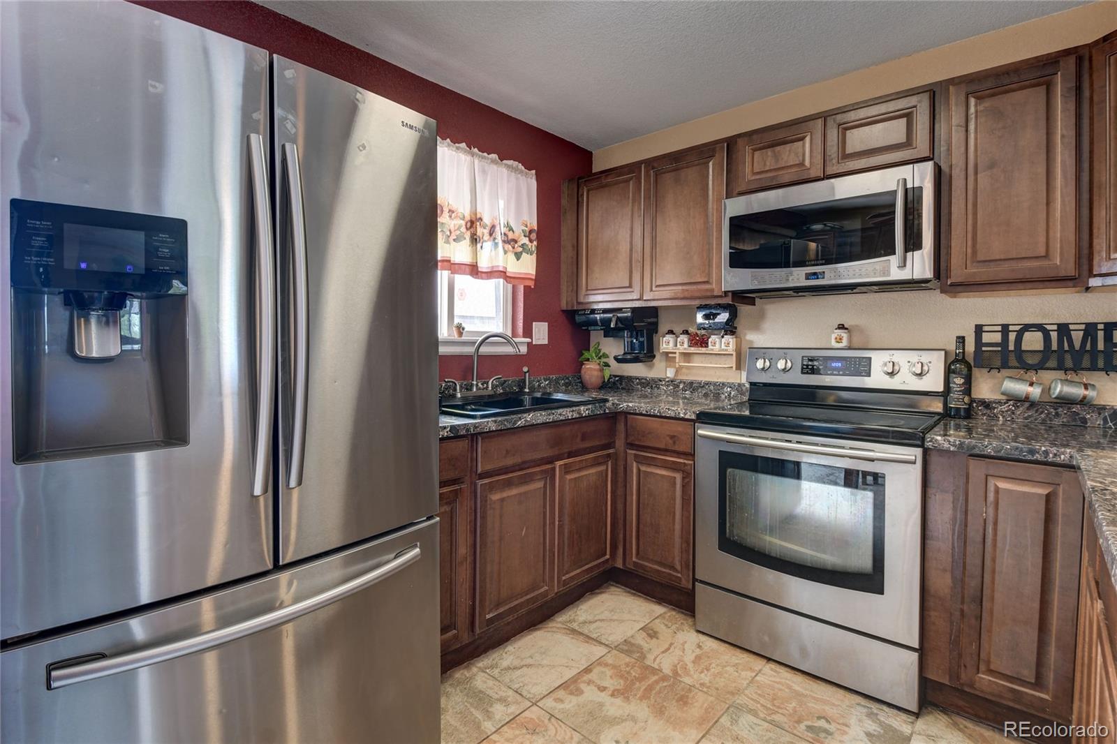 820 South Denver Avenue Fort Lupton, CO 80621 - Photo 2 of 40 a kitchen with granite countertop a refrigerator stove and microwave