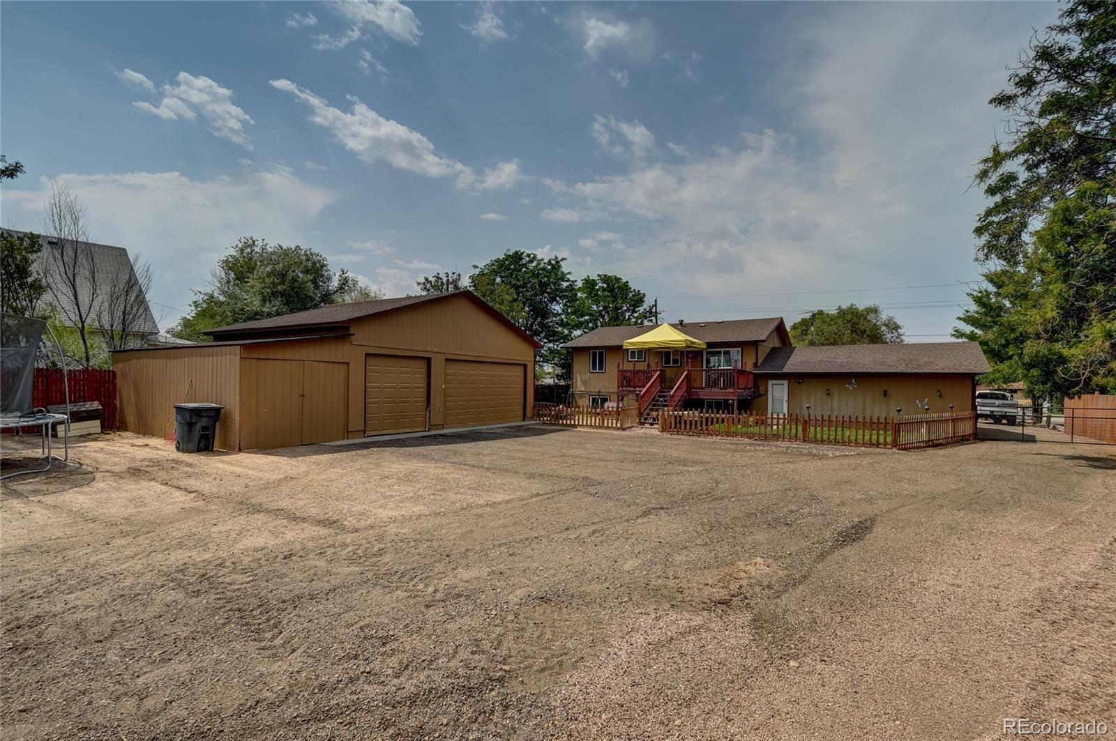 820 South Denver Avenue Fort Lupton, CO 80621 - Photo 24 of 40 a backyard of a house with table and chairs plants and large tree