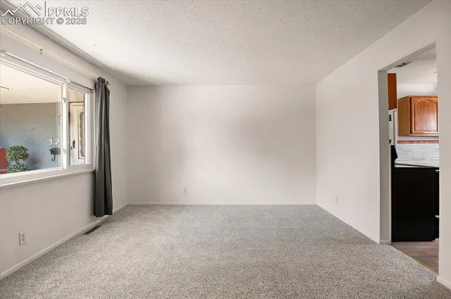 a view of an empty room with window and cabinet