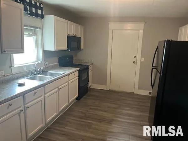 a kitchen with a sink cabinets and a wooden floor