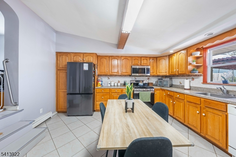 828 Allen Street Linden, NJ 07036 - Photo 9 of 18 a large kitchen with stainless steel appliances granite countertop a refrigerator a sink dishwasher a dining table and chairs with wooden floor