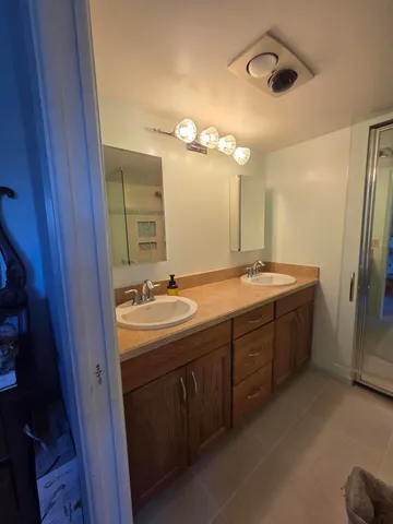 a bathroom with a double vanity sink and mirror with shower