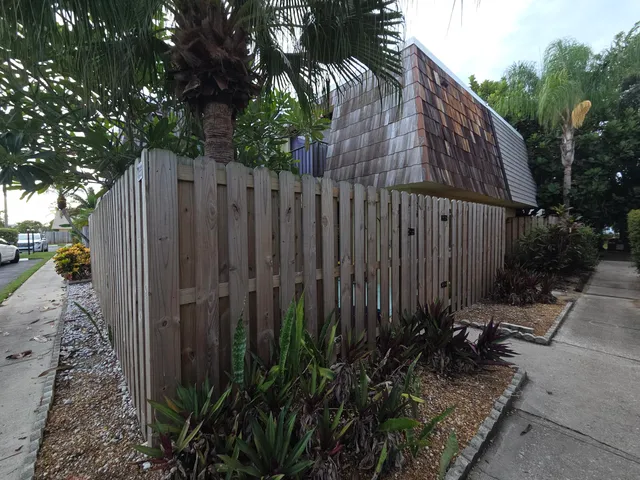 a view of a backyard with potted plants and wooden fence