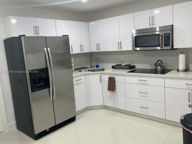 a kitchen with stainless steel appliances white cabinets and a refrigerator