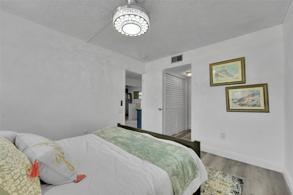 9090 Lime Bay Boulevard, Unit 112 Tamarac, FL 33321 - Photo 18 of 55 a bedroom with a bed and a chandelier
