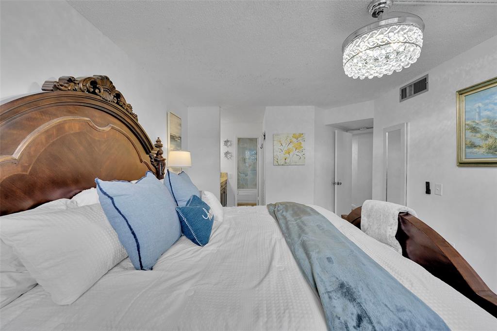 9090 Lime Bay Boulevard, Unit 112 Tamarac, FL 33321 - Photo 23 of 55 a bedroom with a bed and a chandelier