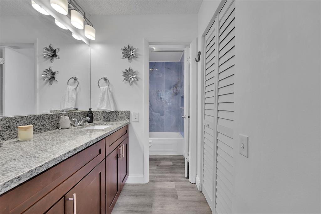 9090 Lime Bay Boulevard, Unit 112 Tamarac, FL 33321 - Photo 24 of 55 a bathroom with a granite countertop sink a mirror and a shower