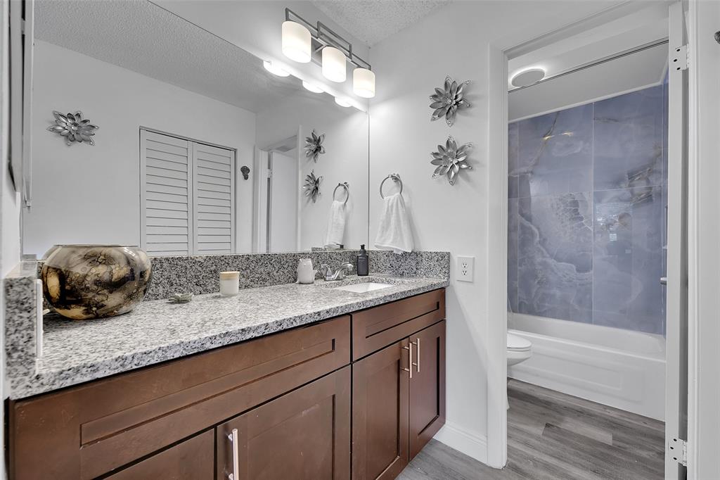 9090 Lime Bay Boulevard, Unit 112 Tamarac, FL 33321 - Photo 25 of 55 a bathroom with a granite countertop sink a toilet a large mirror and shower
