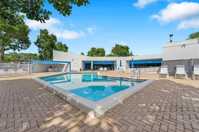 a view of swimming pool with outdoor seating and house in the background