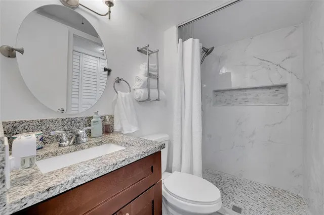 a bathroom with a granite countertop sink toilet and shower