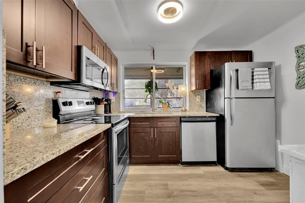 9090 Lime Bay Boulevard, Unit 112 Tamarac, FL 33321 - Photo 10 of 55 a kitchen with stainless steel appliances granite countertop a refrigerator a stove and a sink