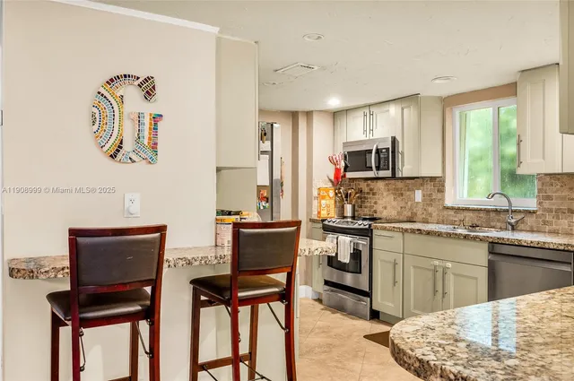 a kitchen with stainless steel appliances granite countertop a stove top oven a sink a dining table and chairs with wooden floor