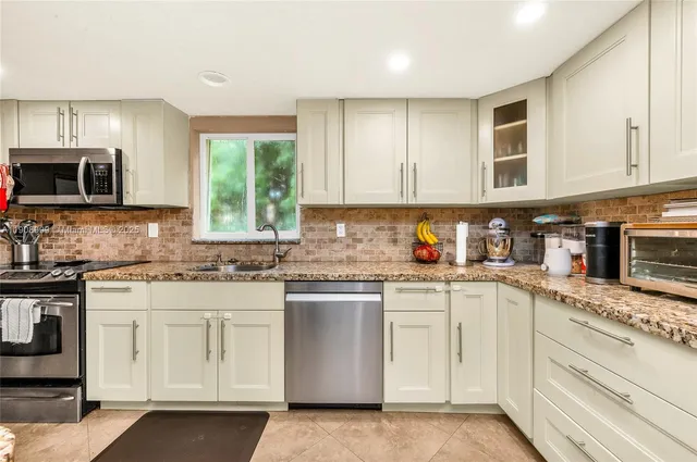 a kitchen with granite countertop white cabinets and white appliances