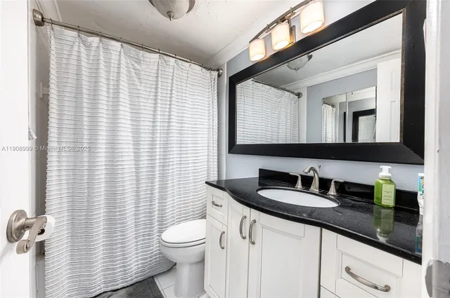 a bathroom with a granite countertop sink toilet and mirror
