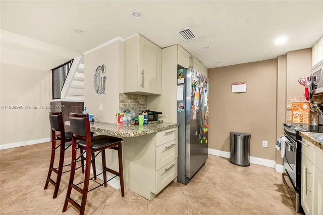 a kitchen with stainless steel appliances kitchen island granite countertop a refrigerator and a stove top oven