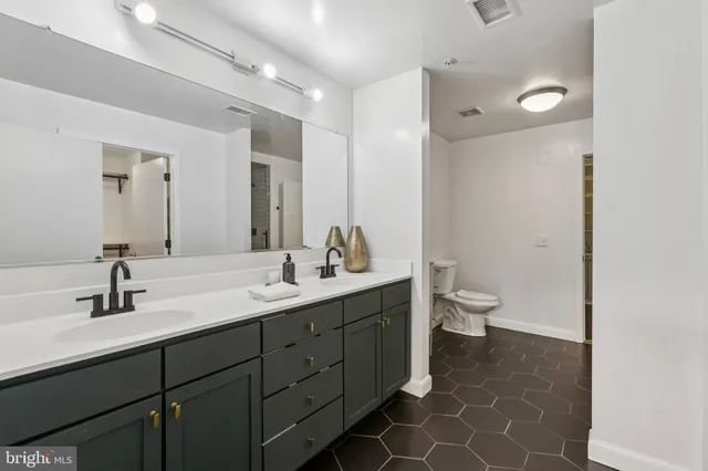 a bathroom with a double vanity sink mirror and toilet