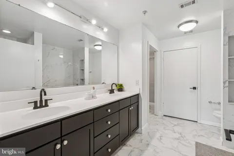 a bathroom with a double vanity sink mirror and next to a window