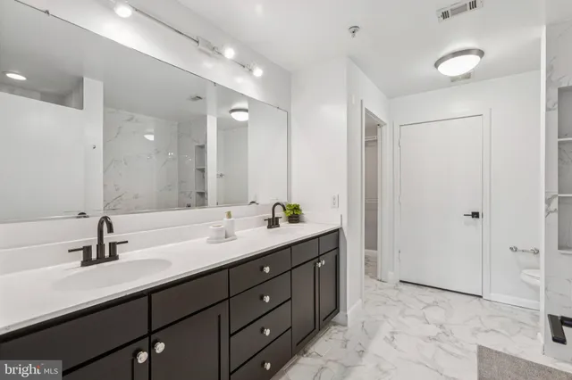 a bathroom with a double vanity sink mirror and next to a window