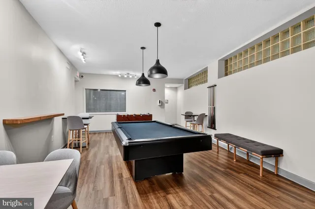 a room with wooden floor pool table and windows