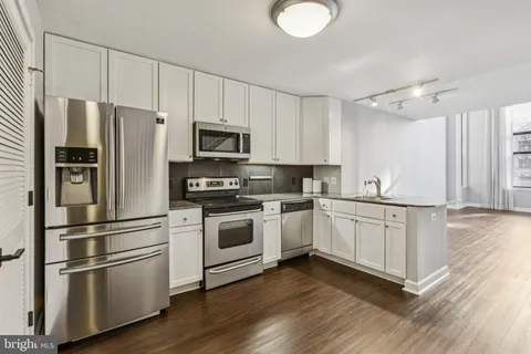 a kitchen with stainless steel appliances white cabinets and a refrigerator