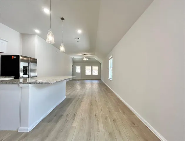 a view of a kitchen with kitchen island a sink wooden floor and a large window