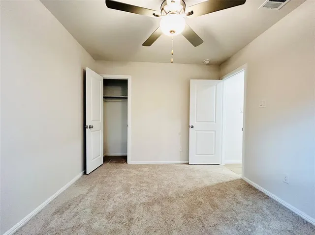 an empty room with a chandelier fan and windows
