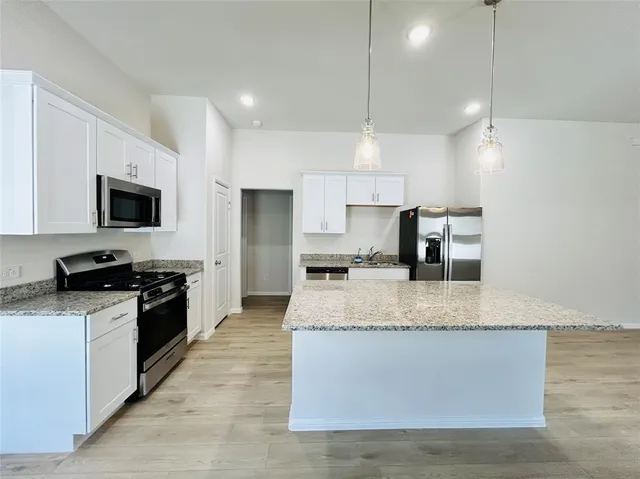 a large kitchen with granite countertop a stove top oven a sink a counter space and cabinets