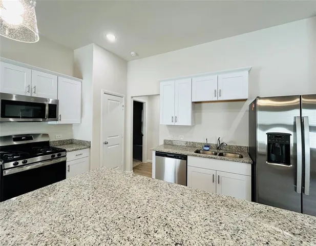 a kitchen with stainless steel appliances granite countertop a refrigerator stove top oven and sink
