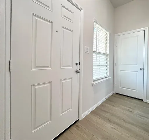 an empty room with wooden floor closet and windows