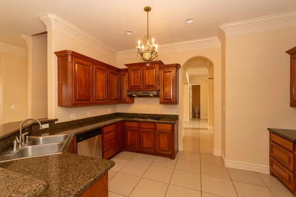 a kitchen with stainless steel appliances granite countertop a sink dishwasher and a stove with wooden cabinets